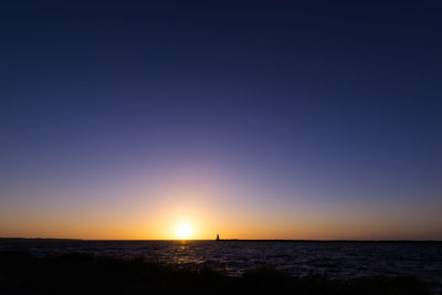 Scenic view of calm sea against clear sky at sunset