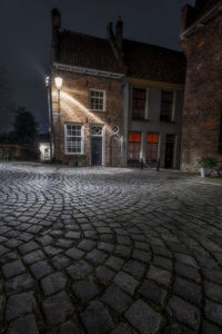 Street by illuminated buildings against sky at night