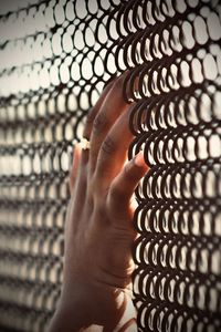 Close-up of person hand on metal fence