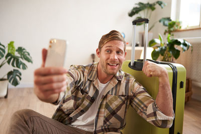 Young woman using phone while sitting on sofa at home