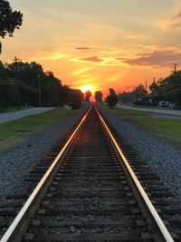 Surface level of railroad tracks against sky during sunset