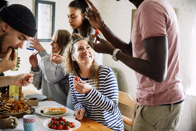 Happy friends enjoying food at social gathering in house