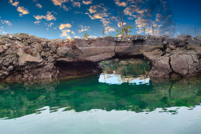 Rock formation by lake against sky