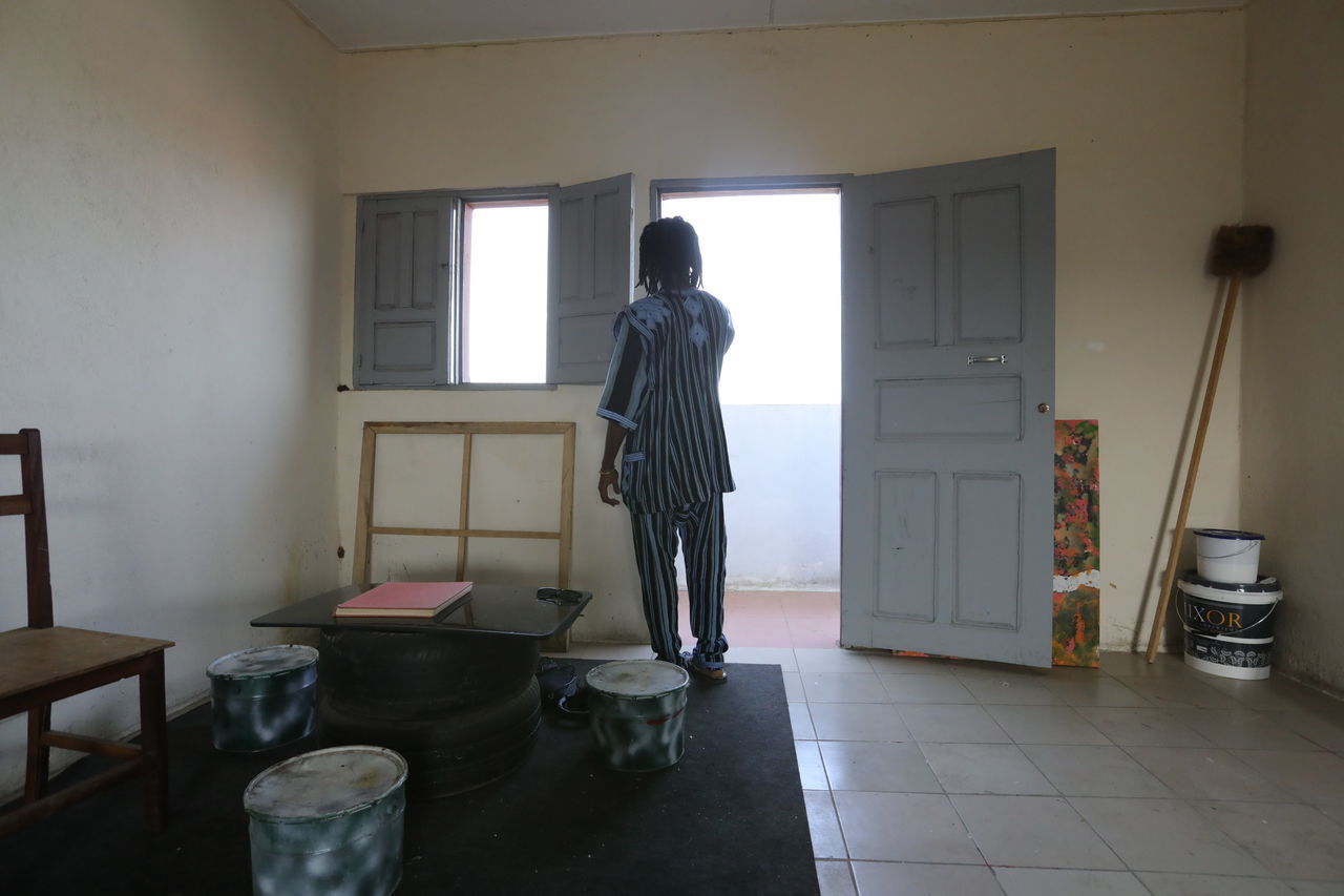 REAR VIEW OF WOMAN STANDING AGAINST DOOR AT HOME