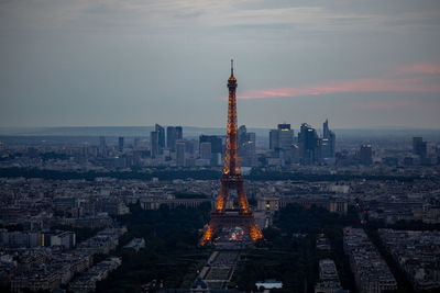 Aerial view of buildings in city against cloudy sky