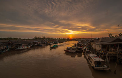 Boats moored at harbor during sunset