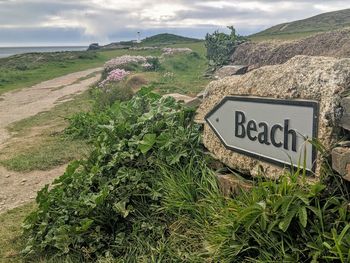 Information sign on field by road against sky