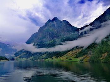 Scenic view of lake by mountains against sky