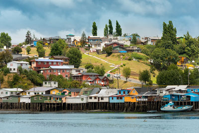 Buildings by swimming pool by river against sky