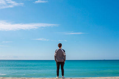 Rear view of man standing in front of sea
