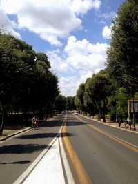 Road amidst trees in city against sky
