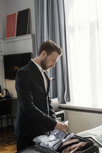 Mature businessman unpacking luggage in hotel room