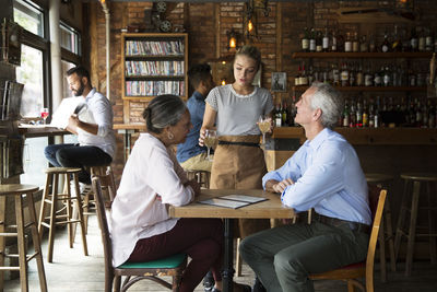 Waitress serving drinks to customers at cafe