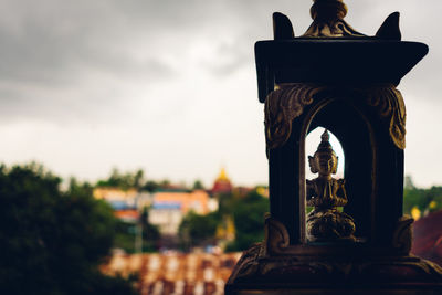 Close-up of buddha statue against sky