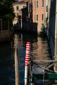 Wooden post in canal amidst buildings