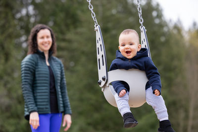 Portrait of smiling young woman swinging at playground