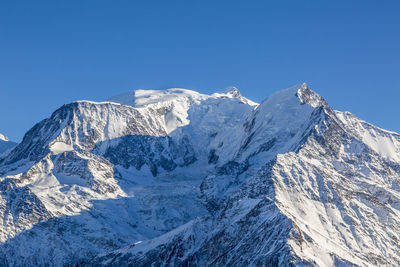 Scenic view of snowcapped mountains against clear blue sky