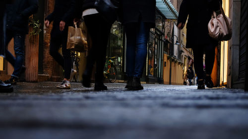 Low section of people walking on street in city