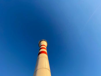 Low angle view of smoke stacks against clear blue sky