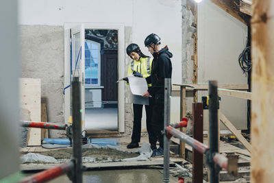 Female engineer discussing with male construction worker at site