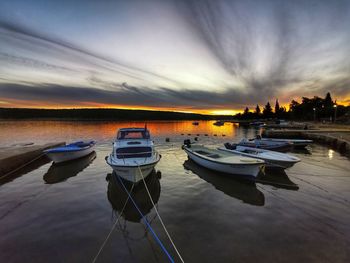 Boats moored in sea against sky during sunset