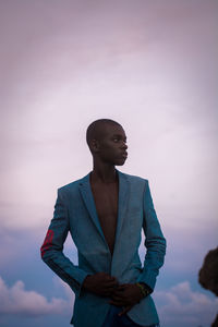 Young man standing against sky in a blazer 