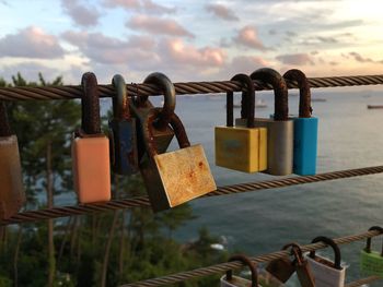 Close-up of locks on railing against sky