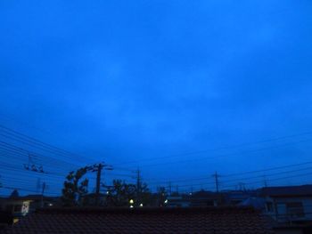 Silhouette electricity pylon against blue sky