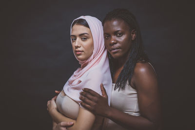 Portrait of women standing against black background