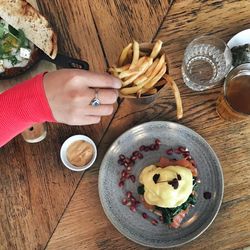 Close-up of woman having french fries on wooden table