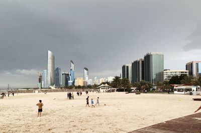 People on beach with city in background