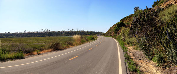 Road by landscape against clear sky