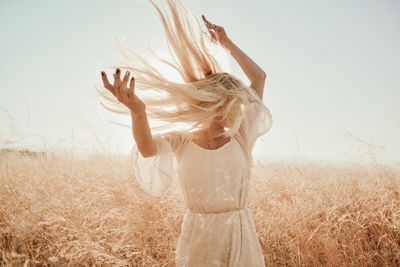 Midsection of woman standing on field against sky