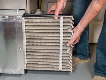 Low angle view of man holding air conditioner filter