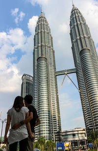 Low angle view of skyscrapers against cloudy sky