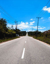 Road by electricity pylon against sky