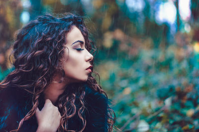 Close-up of young woman in forest during rainfall