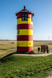 Lighthouse on field against clear sky