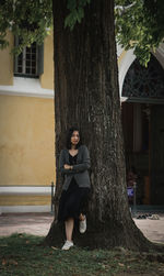 Portrait of young woman standing against trees