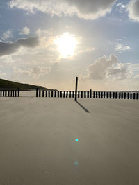 Wooden posts on beach against sky during sunset
