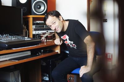 Portrait of man sitting on chair by sound mixer at recording studio