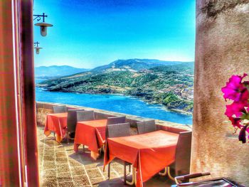 Chairs on beach by sea against clear blue sky