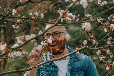 Low angle view of young man holding cherry blossom