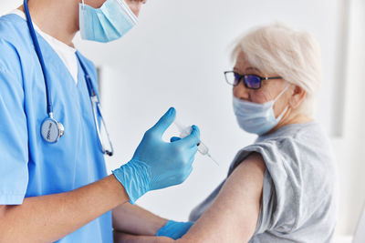 Doctor wearing mask vaccinating patient