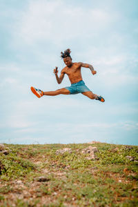 Low angle view of man jumping on field against sky