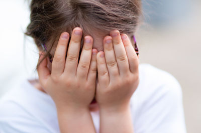Close-up of girl covering face with hands