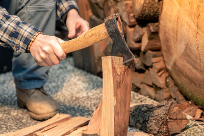 Man uses ax to break wood to use for bbq wood to light fire to cook food on grill hands holding tool