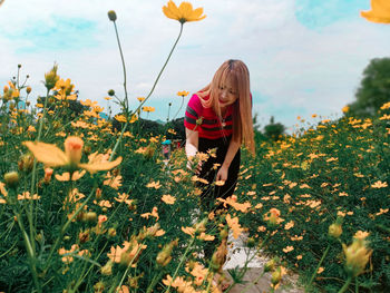 Low angle view of woman amidst flowering plants on field