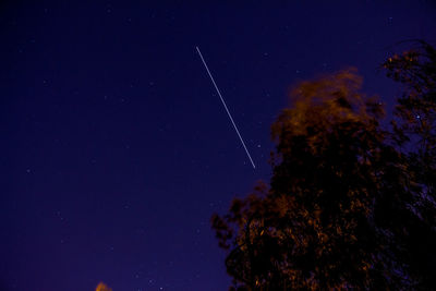 Low angle view of vapor trails in sky at night