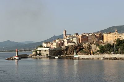 Scenic view of sea by buildings against clear sky